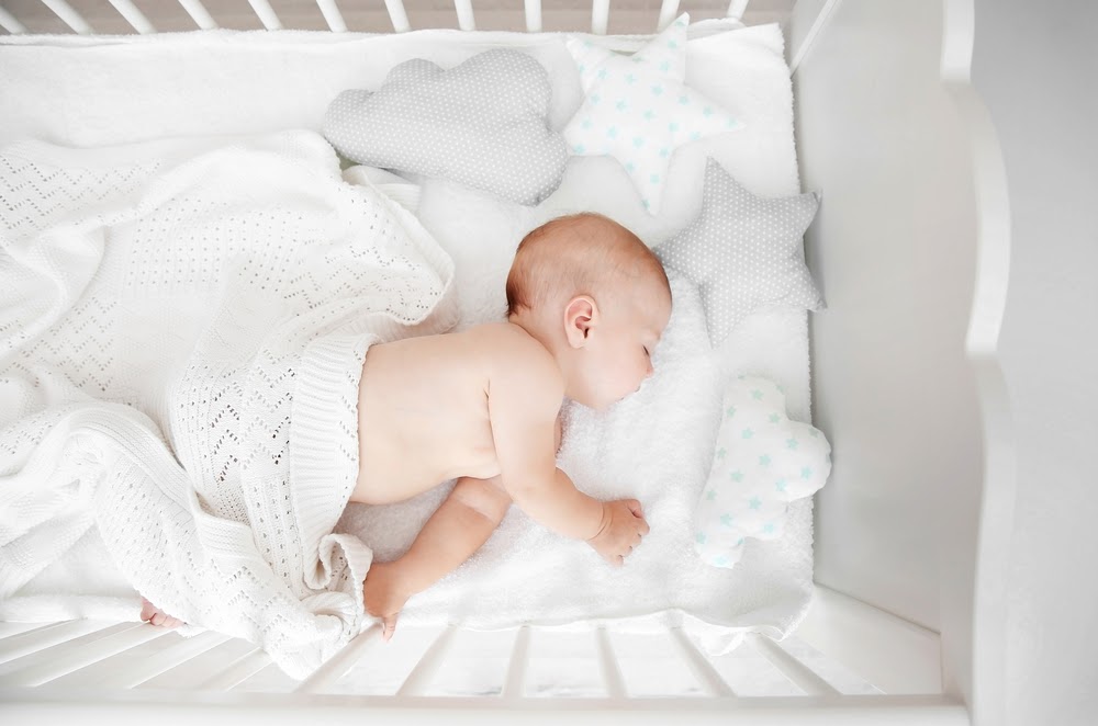 baby sleeping in white cot