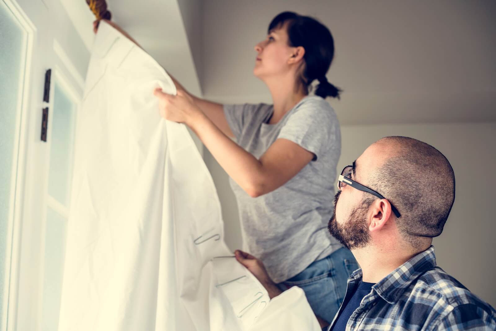 man and woman hanging up curtains