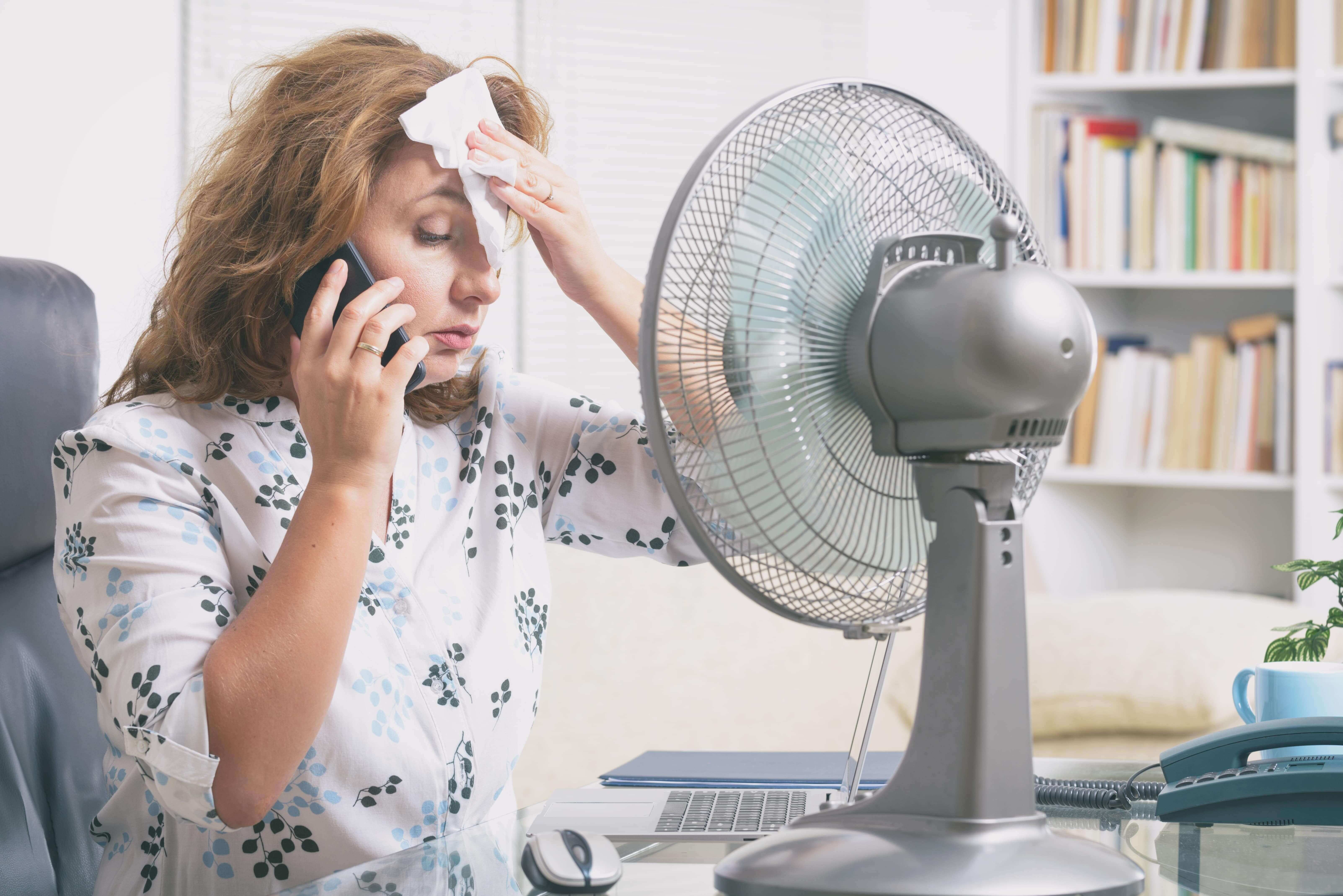 woman sweating in front of fan