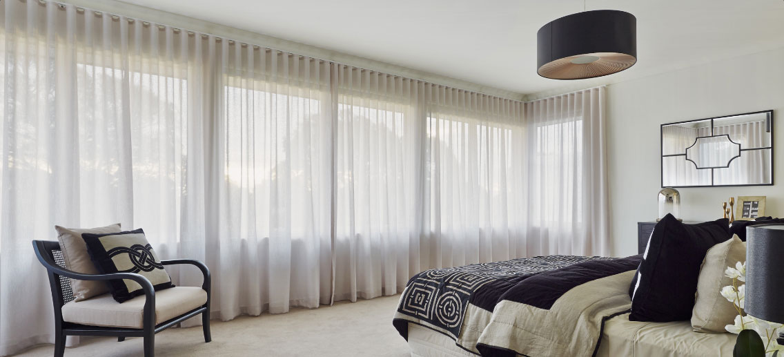 white curtains across large bedroom window